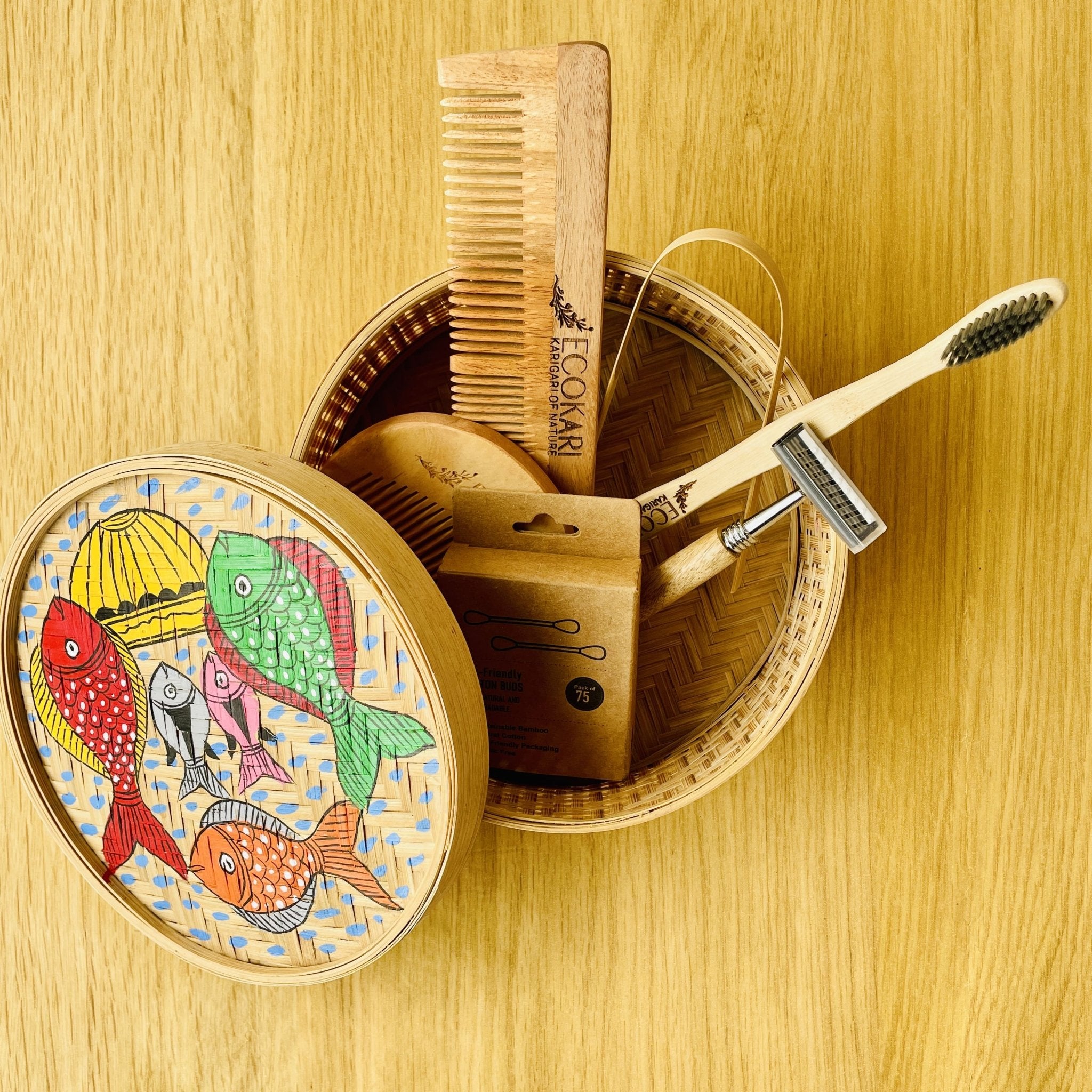 Men's neem wood beard comb, unisex neem wooden comb, cotton bamboo earbuds, tongue cleaner, bamboo toothbrush, bamboo wooden shaving razor packed in a bamboo box hand painted with fish paintings in traditional Pattachitra art form style.