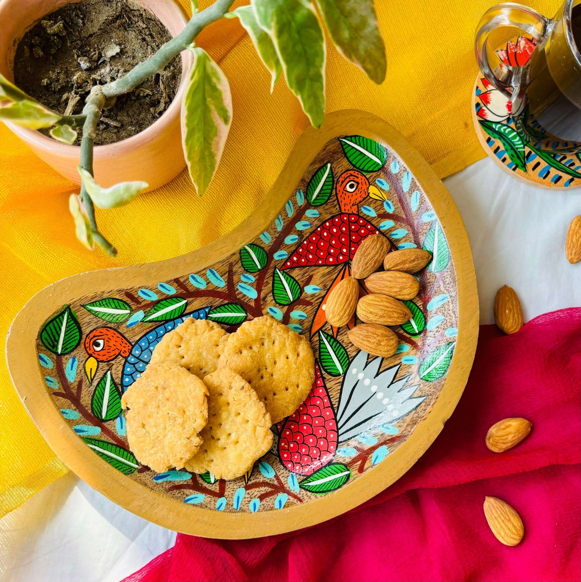 Biscuits and almonds are served in a handcrafted mango wood moon-shaped wooden tray for the kitchen or trinket tray, painted with three bird motifs by generational Pattachitra artists