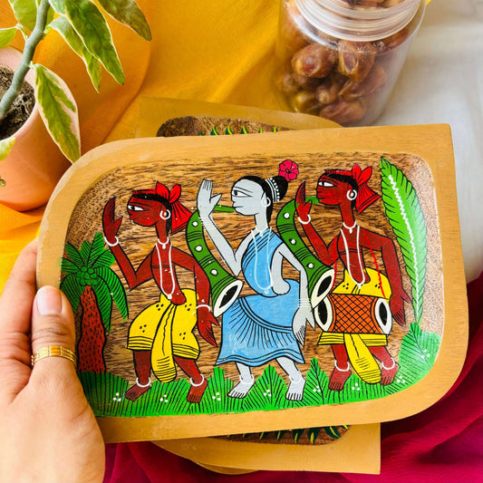Hand holding rectangular wooden tray or trinket tray handcrafted from mango wood and featuring tribal motif, hand painted by the generational Pattachitra artists of Pingla