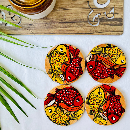 Four pure mango wood round wooden coasters, with a painting of one yellow fish and one redfish along with an Indian classical musical instrument in each wood coaster