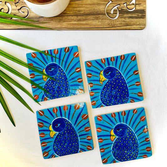 Four pure mango wood square wooden coasters, with a painting of peacocks with blue bodies, red feathers and yellow beaks
