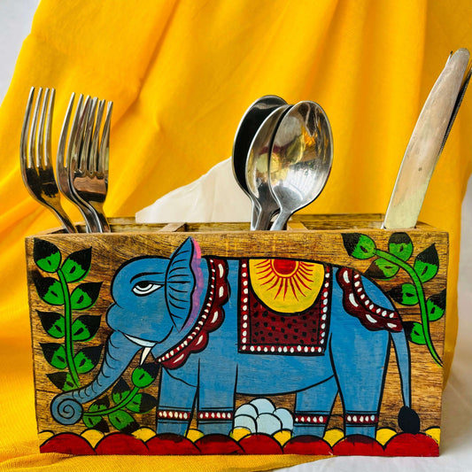 Three spoons, three forks and three knives organised in a pure mango wood cutlery holder showcasing pattachitra painting of an elephant surrounded by tree branches and leaves.