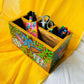 An aerial view of three pens, two scissors, six coloured pens and a bookmark placed in a 9”x5”x3” pure mango wood table organiser or wood cutlery holder wooden tissue holder with 3 small and one large compartment, handcrafted by rural artisans and painted with two peacocks, tree branches and leaves motifs