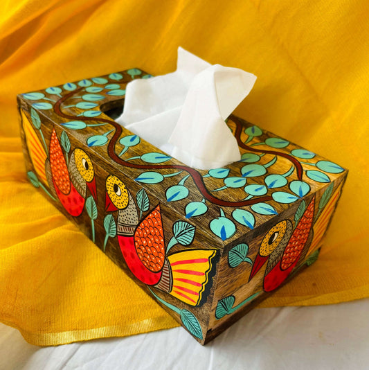 A pure mango wood wooden tissue holder, with two birds, and leaves hand painted on it, placed at an angle with a yellow background