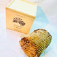 100% natural soy wax scented candle wrapped in honeycomb paper near a wood candle box.
