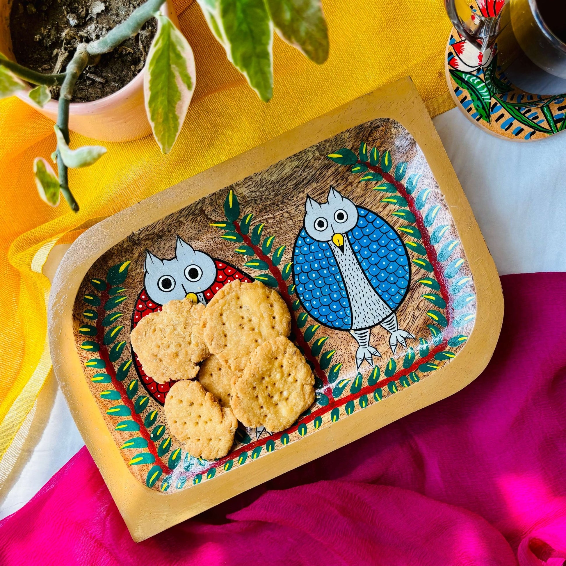 Snacks served in a handcrafted pure mango wood rectangular wood platter, painted with two owl motifs by generational Pattachitra artists