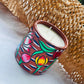 100% natural soy wax scented candle in a terracotta jar, hand painted with four lotus motifs, is placed near a honeycomb paper